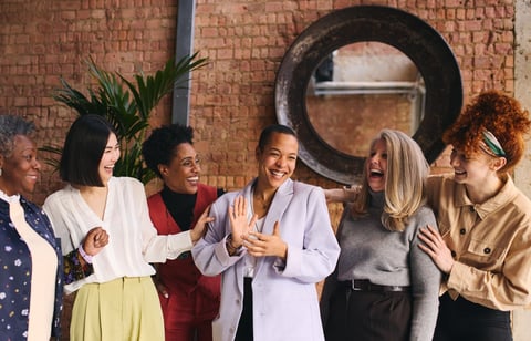 International Women's Day portrait of cheerful multi ethnic mixed age range businesswomen celebrating together