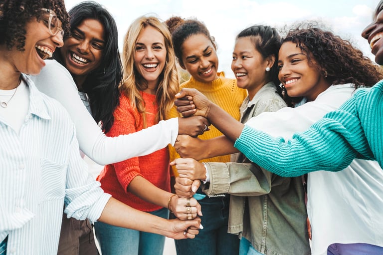 Multicultural group of women stacking hands together supporting each other outdoors