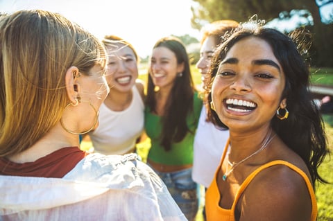 Happy group of young women hugging together outside smiling at camera showing friendship and female community