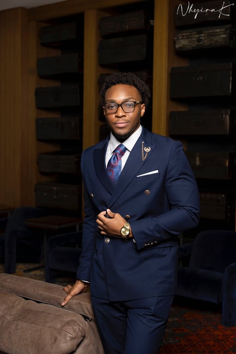 Professional portrait of Ezekiel, co-founder of Restoration Living, in a navy double-breasted suit with glasses